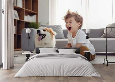 A little boy laughing as he plays fetch with his mixed breed puppy in a bright, minimalist living room. Wall mural