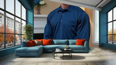 A smiling American man in his late thirties wears glasses and a blue dress shirt, standing next to a couch in a hotel lobby with warm lighting and stylish decor. Wall mural