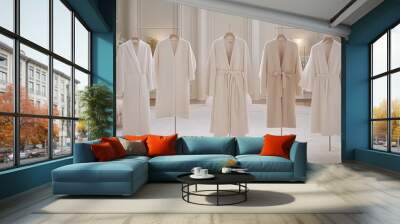 A variety of garments, including coats and dresses in neutral hues, are elegantly arranged on a rack against a stylish gray backdrop Wall mural