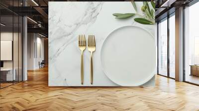 A white marble tabletop with a white plate, gold fork, gold knife, and gold spoon. An olive branch with green leaves extends from the left side of the frame Wall mural