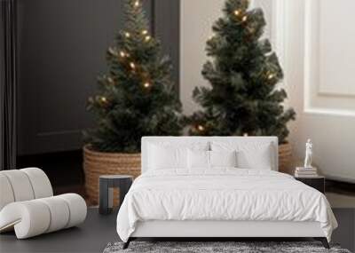 Small Christmas trees adorned with lights and garlands sit in wicker baskets beside an elegant bedside lamp. A decorative chest and natural light create a warm atmosphere in the room Wall mural