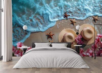 two straw hats, delicate pink flowers, and starfish on a sandy beach, with waves gently crashing in an aerial perspective, adorned with soft lighting and a soothing blue color palette. Wall mural