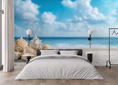 Various seashells rest on golden sand, illuminated by sunlight, with the serene ocean and bright clouds in the background Wall mural