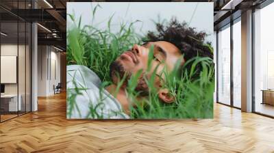 a man lying on green grass with eyes closed Wall mural