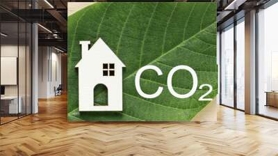 Decarbonization of Real Estate. Lower CO2 emissions and reduce carbon. House, letter CO2 on green leaf background. Sustainable development, environment protection Wall mural