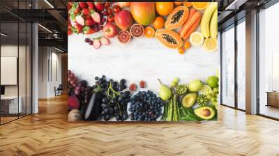 Healthy eating background, different varieties of colourful fruits and vegetables in rainbow colours on the off white table with copy space in the middle, top view, selective focus Wall mural