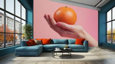 A hand holding an orange Wall mural