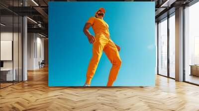 A man in a yellow outfit is standing on a blue surface Wall mural