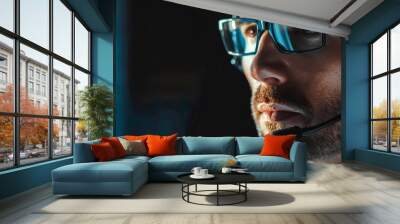 A man wearing glasses and a headset is looking at a computer screen Wall mural