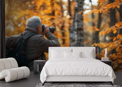 A man with a backpack and a camera is taking a picture of a tree Wall mural