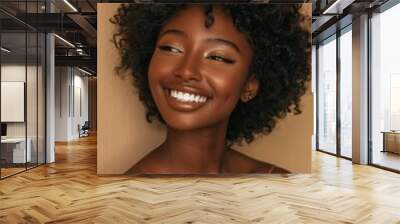 A woman with curly hair is smiling and looking at the camera Wall mural