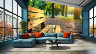 A wooden bench in a park with leaves on the ground Wall mural