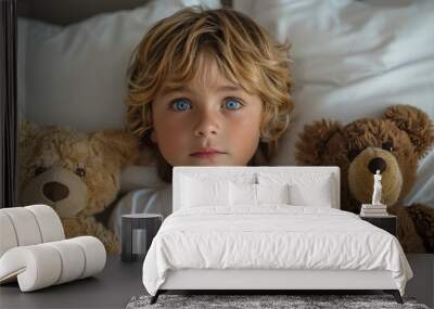 A young boy is laying on a bed with two teddy bears, one brown and one tan Wall mural