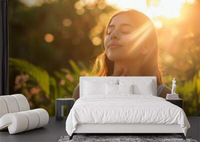 A young Mexican woman enjoys nature, meditates with her eyes closed, inhales fresh air in a beautiful garden at sunset. Health, Nature, Tranquility, Relaxation, The Power of the concept Wall mural