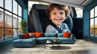 Close-up of a happy handsome little boy sitting in a child car seat in a car. Wall mural