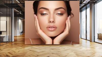 Close-up of a young woman with half-open eyes, makeup, pink lips, holding her face, head with two hands on a beige background. Natural Beauty, Facial skin care, cosmetics, lipstick, cream concepts. Wall mural