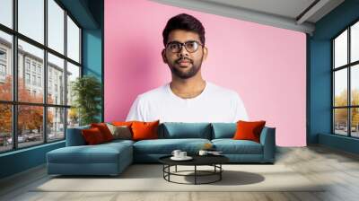 Portrait of handsome Indian guy standing on pink background Wall mural