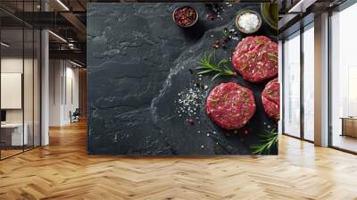 Three pieces of meat are on a black counter with a bowl of salt and pepper Wall mural