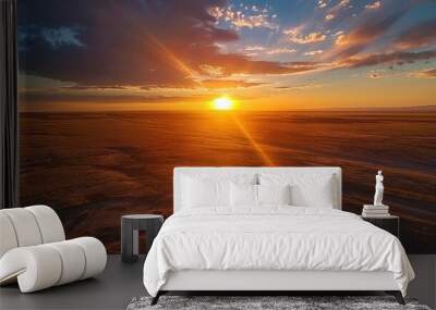 A breathtaking sunrise over a vast, open plain, with the sun rising over the horizon, casting a long shadow across the flat landscape Wall mural