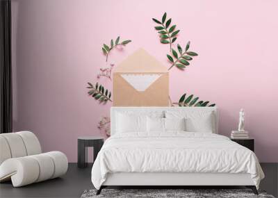 Mockup with craft envelope and green leaves on pink background. Minimal styled flat lay in pastel colors. Wall mural