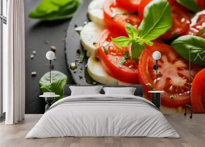 Close up of Italian Caprese salad featuring ripe tomatoes mozzarella cheese and fresh basil on black background Wall mural