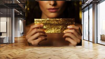 Closeup of woman holding shiny gold bar on sequin fabric Wall mural