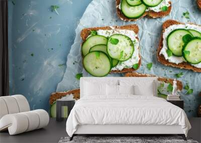 Open faced rye bread bruschetta with cream cheese ricotta and cucumber on white wax paper Healthy and delicious meal or snack Blue background Wall mural