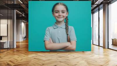 Smiling Caucasian teen girl with braided hair in polo shirt standing on turquoise background Wall mural