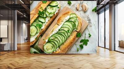 Top view of fresh cucumber and baguette slices on cutting board accompanied by cream cheese and parsley sandwich on a rustic wooden background Wall mural