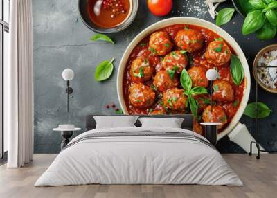 Top view of homemade meatballs in white pan on grey background with copy space garnished with tomato sauce and spices Wall mural