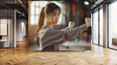 Young woman practicing tai chi chuan in gym harnessing Chinese energy Wall mural