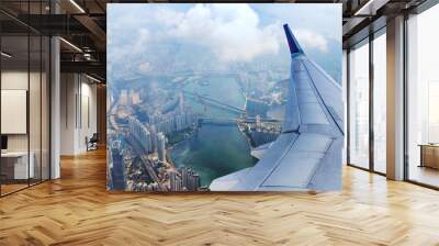 Airplane flies over Hong Kong. Passenger jet plane flying above urban scene. Hongkong flight. Asian destination. Wall mural