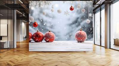 Red Christmas balls hanging and standing on white wooden board ground covered with snow with abstract spruce trees and snowfall in the background. Wall mural