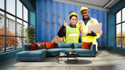 Young African american men and woman worker Check and control loading freight Containers by use computer laptop at commercial shipping dock felling happy. Cargo freight ship import export concept Wall mural