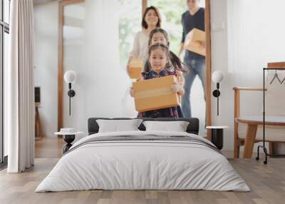 Young Asian family with daughter holds carton and walking in to a new home in moving relocation day which Excited smiling and felling happy. Mother Father and daughter move on a new home concept. Wall mural