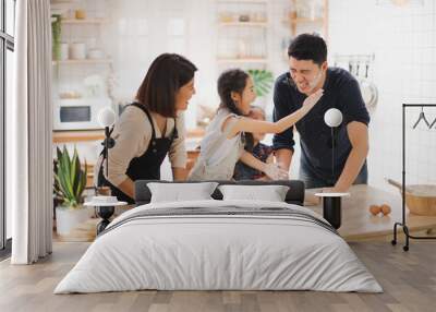 Young Asian love family are preparing the dough powder, cookies, cake on table in the kitchen which Excited smiling and felling happy. parent and daughter are cooking on the day at home. Wall mural