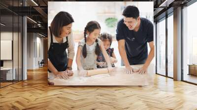 Young Asian love family are preparing the dough powder, cookies, cake on table in the kitchen which Excited smiling and felling happy. parent and daughter are cooking on the day at home. Wall mural