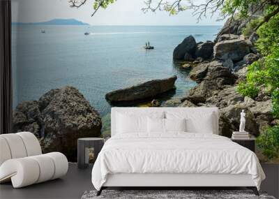 beautiful view on rocky seacoast with fishmen on islands and motor boat Wall mural