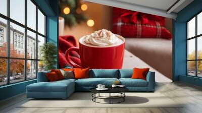 A red cup of cocoa, hot chocolate or coffee with whipped cream on a wooden table with red knitted plaid in front of a Christmas tree. Merry Christmas or New Year concept for banner with copy space. Wall mural