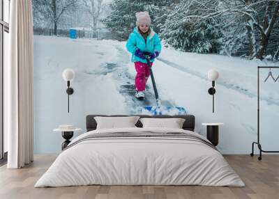 A young girl shoveling snow in a winter storm Wall mural