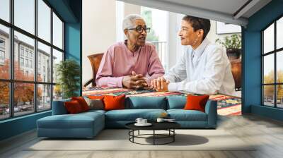 Elderly woman talks with her adult daughter sitting at a table at home Wall mural