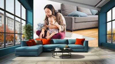 Woman Reading Book While Daughter Sitting On Lap Wall mural