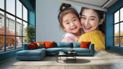 cheerful asian toddler daughter hugging happy mother isolated on gray AI generated Wall mural