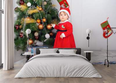 Cute little girl in Santa's suit near a Christmas tree Wall mural