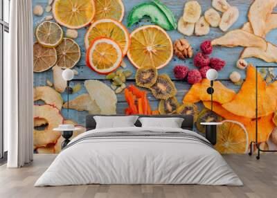 Dried fruit and vegetable chips, candied pumpkin slices, nuts and seeds on blue wooden background Wall mural