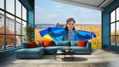 Girl wearing national dress and wreath of flowers holding flag of Ukraine Wall mural