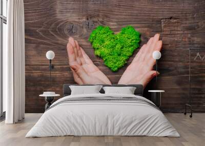 Heart shape stabilized moss in female hands on dark wooden background Wall mural