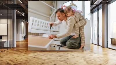 Little girl helping her father assemble the drawer of bed Wall mural