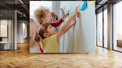 Preschool students playing in kindergarten with color dinosaur figures Wall mural