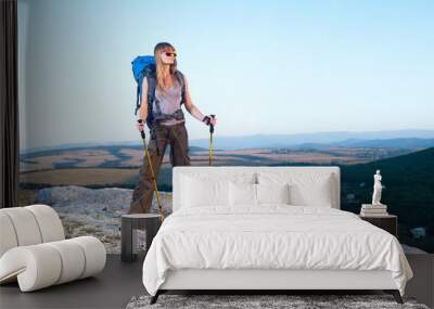 Smiling young woman standing on the top of mountain Wall mural